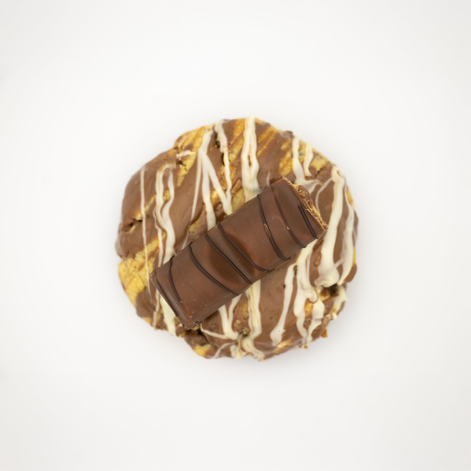 Cookie topped with Kinder chocolate and white drizzle, shot from above