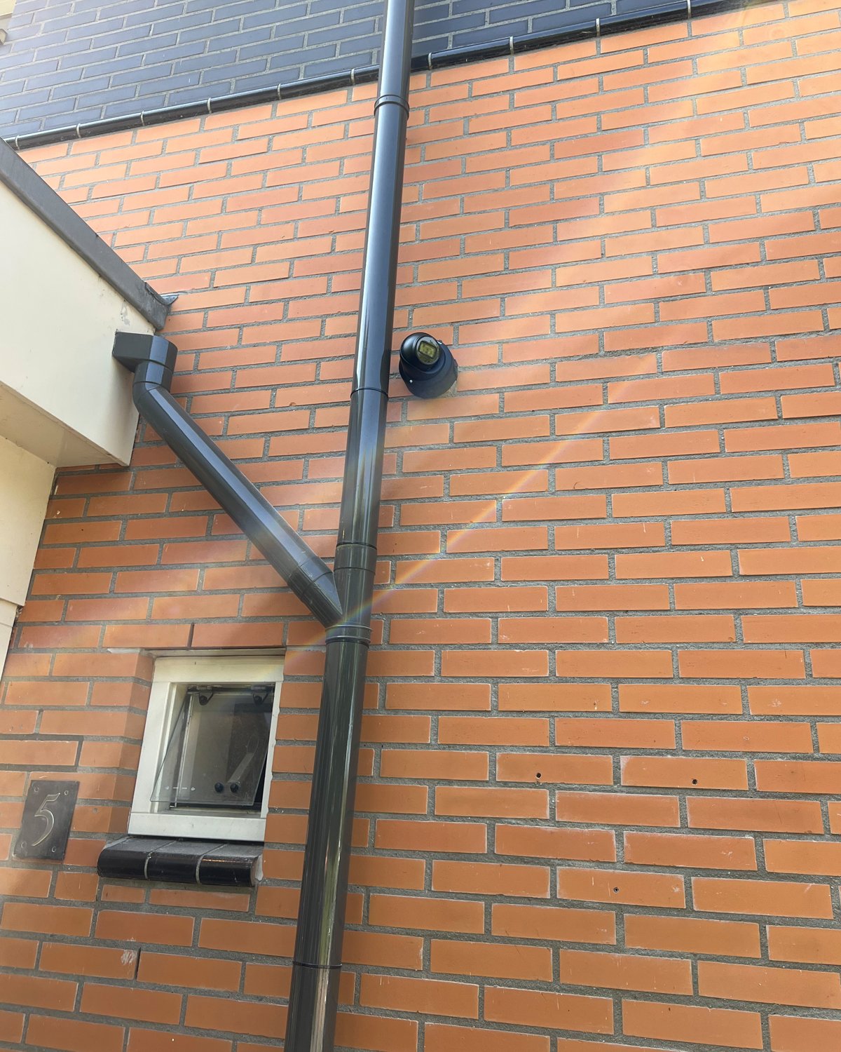 A dome camera mounted on a brick façade beside a window