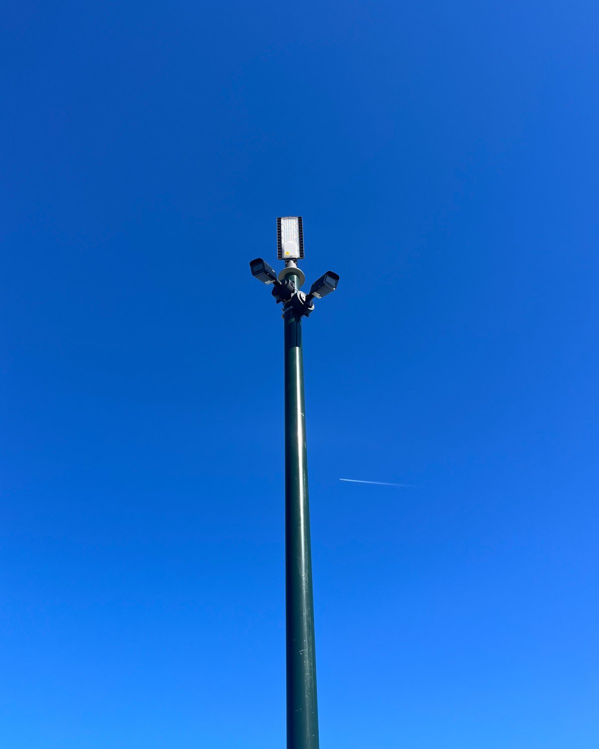 A camera pole with three cameras against a deep blue sky