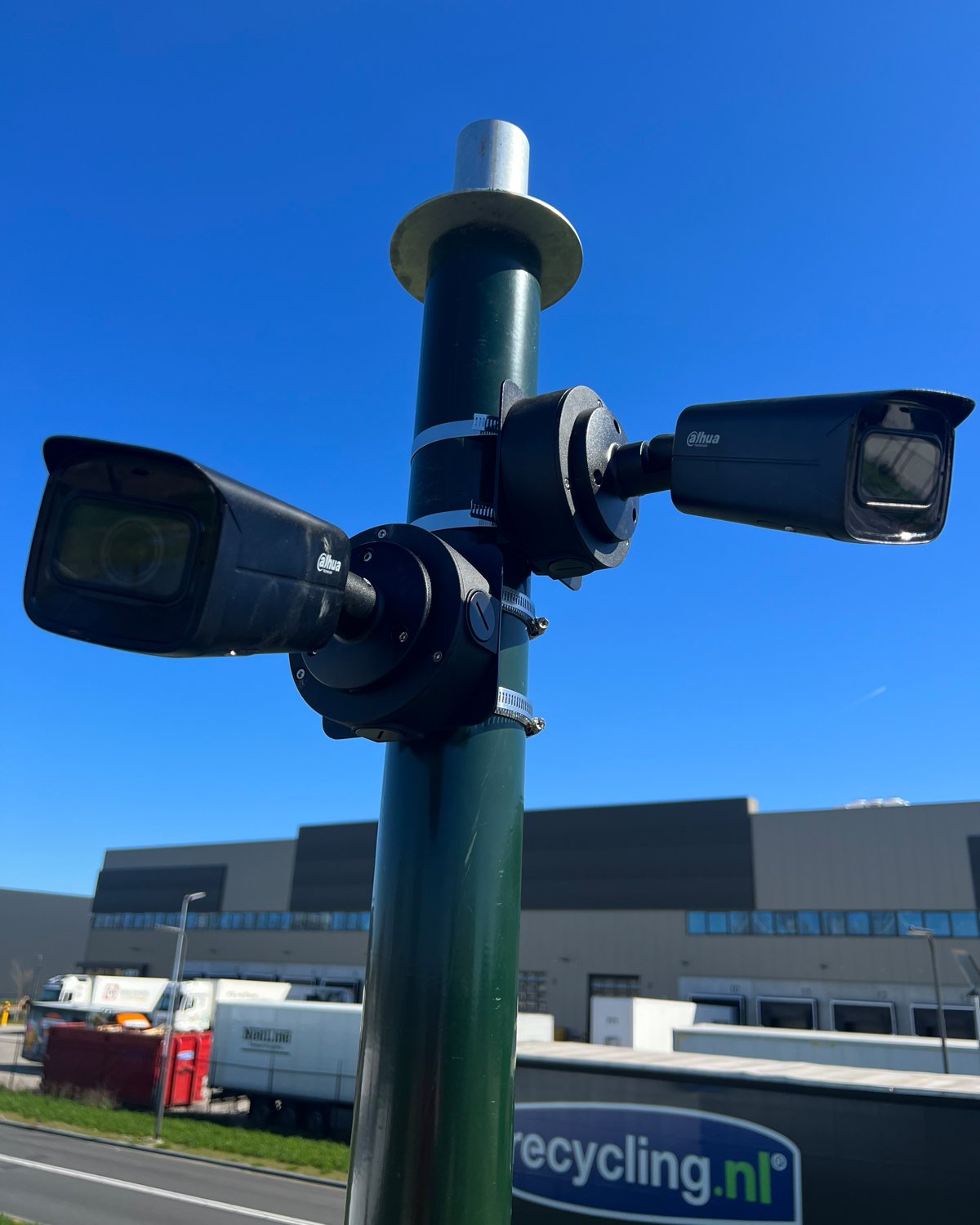 Close-up of a three-camera mount on a pole at a recycling yard